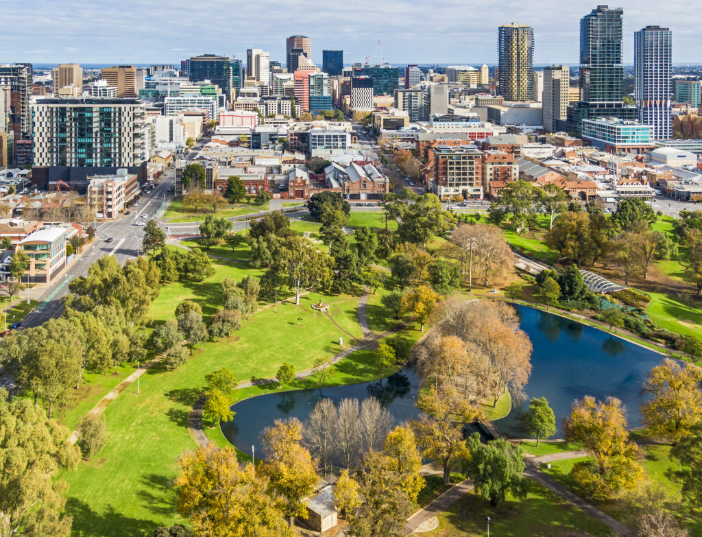 Aerial close view east side of Adelaide with beautiful Rymill Park adjacent in foreground: vibrant green colours, sunny, connection between city and environment, wellbeing, recreation, conservation, autumn colours, fresh air.