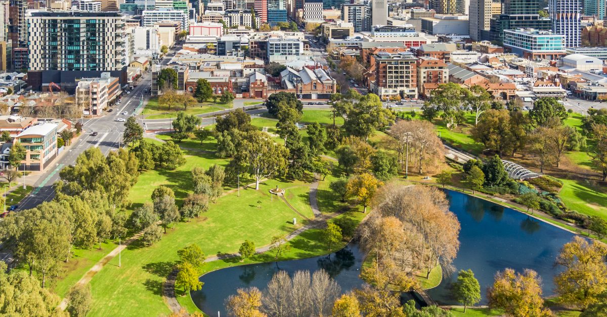Aerial close view east side of Adelaide with beautiful Rymill Park adjacent in foreground: vibrant green colours, sunny, connection between city and environment, wellbeing, recreation, conservation, autumn colours, fresh air.